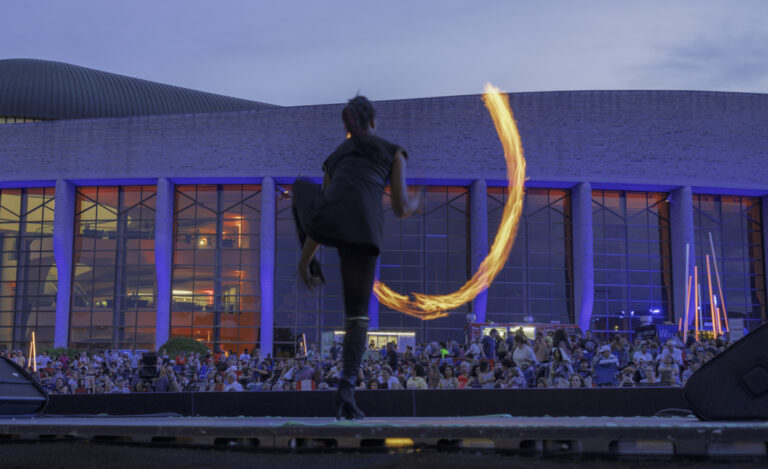 Artiste qui fait une prestation avec du feu devant une foule.