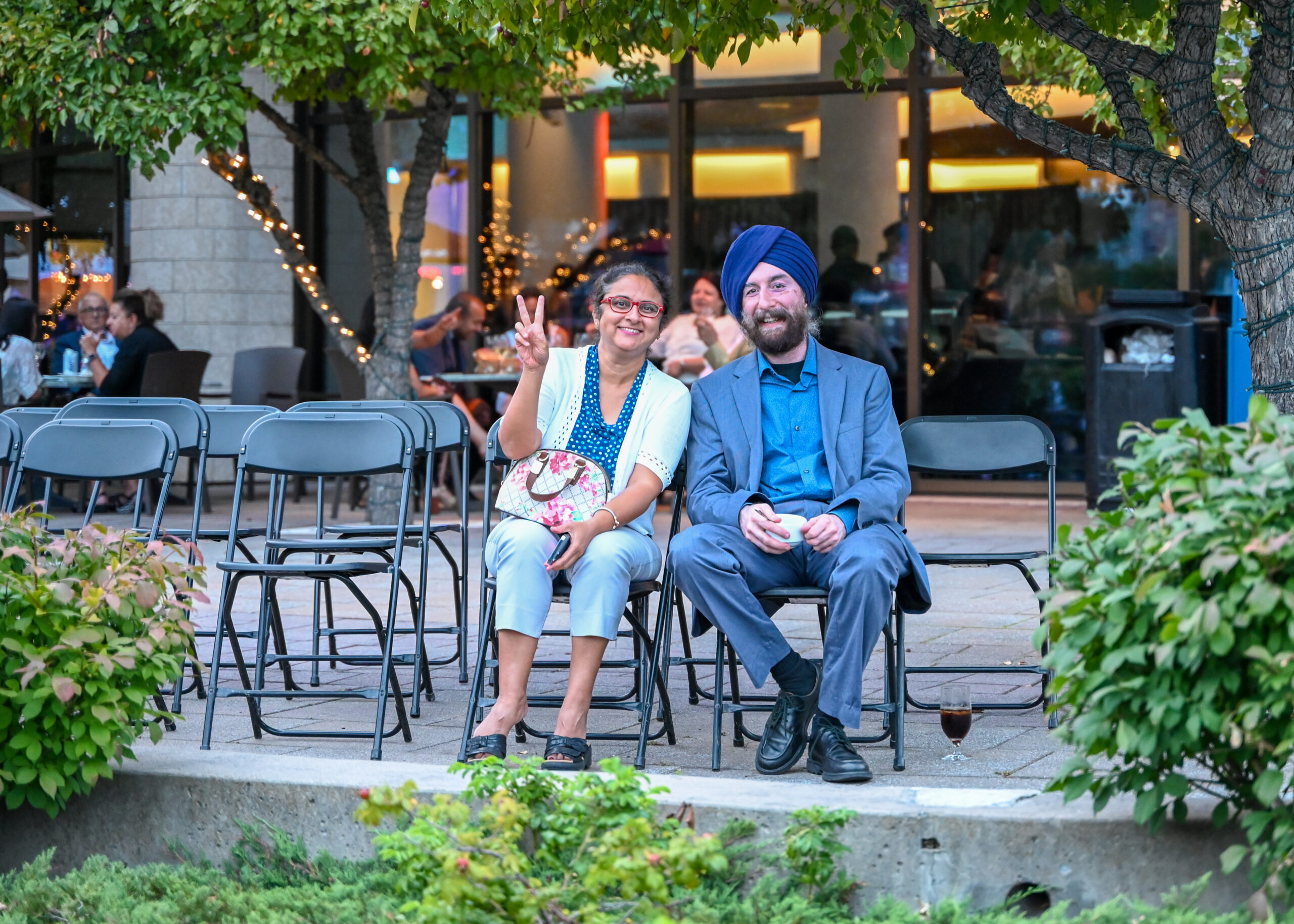 Une femme et un homme en tenus formelles assis sur les chaises de la terrasse du Café Panorama.